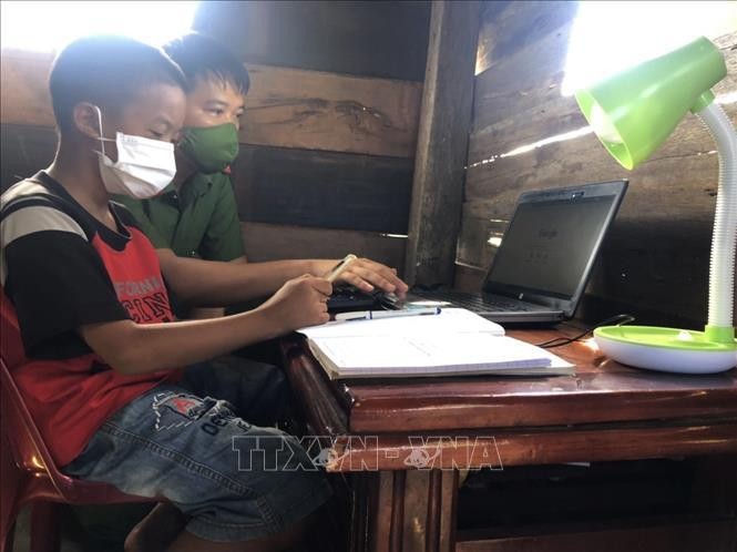 Thiếu tá Lê Anh Tuấn, Đội tổng hợp Công an huyện Cư M’Gar hướng dẫn học sinh có hoàn cảnh khó khăn sử dụng laptop do anh trao tặng. Ảnh minh họa: TTXVN phát.