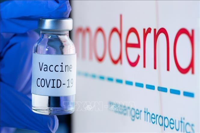 Vaccine ngừa COVID-19 bên biểu tượng của Hãng dược phẩm Moderna. Ảnh: AFP/TTXVN