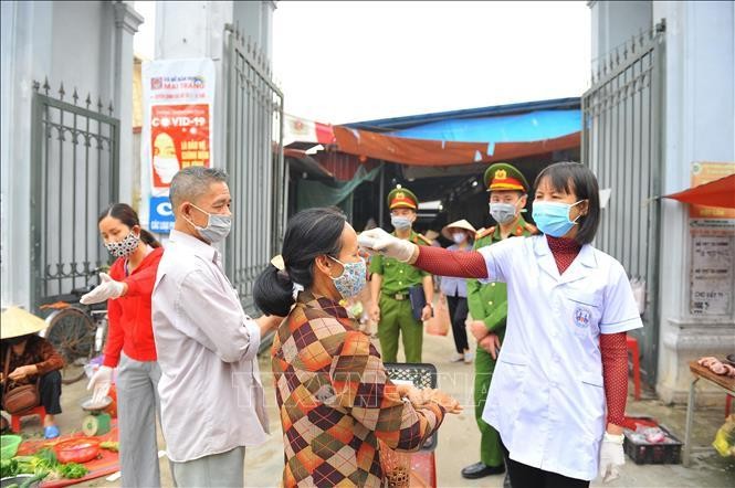 Chốt phòng, chống dịch với cán bộ y tế, công an kiểm tra thân nhiệt cho người dân trước khi vào chợ tại huyện Hoa Lư (Ninh Bình). Ảnh: Minh Đức/TTXVN