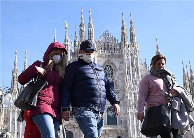 Khách du lịch đeo khẩu trang phòng dịch COVID-19 khi thăm quan Nhà thờ lớn Duomo tại Milan, Italy. Ảnh tư liệu: THX/TTXVN