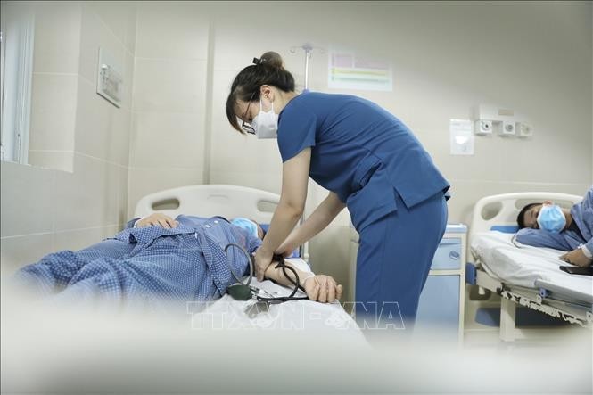 Điều dưỡng chăm sóc bệnh nhân đang điều trị cúm A tại bệnh viện Thanh Nhàn. Ảnh: Minh Quyết/TTXVN